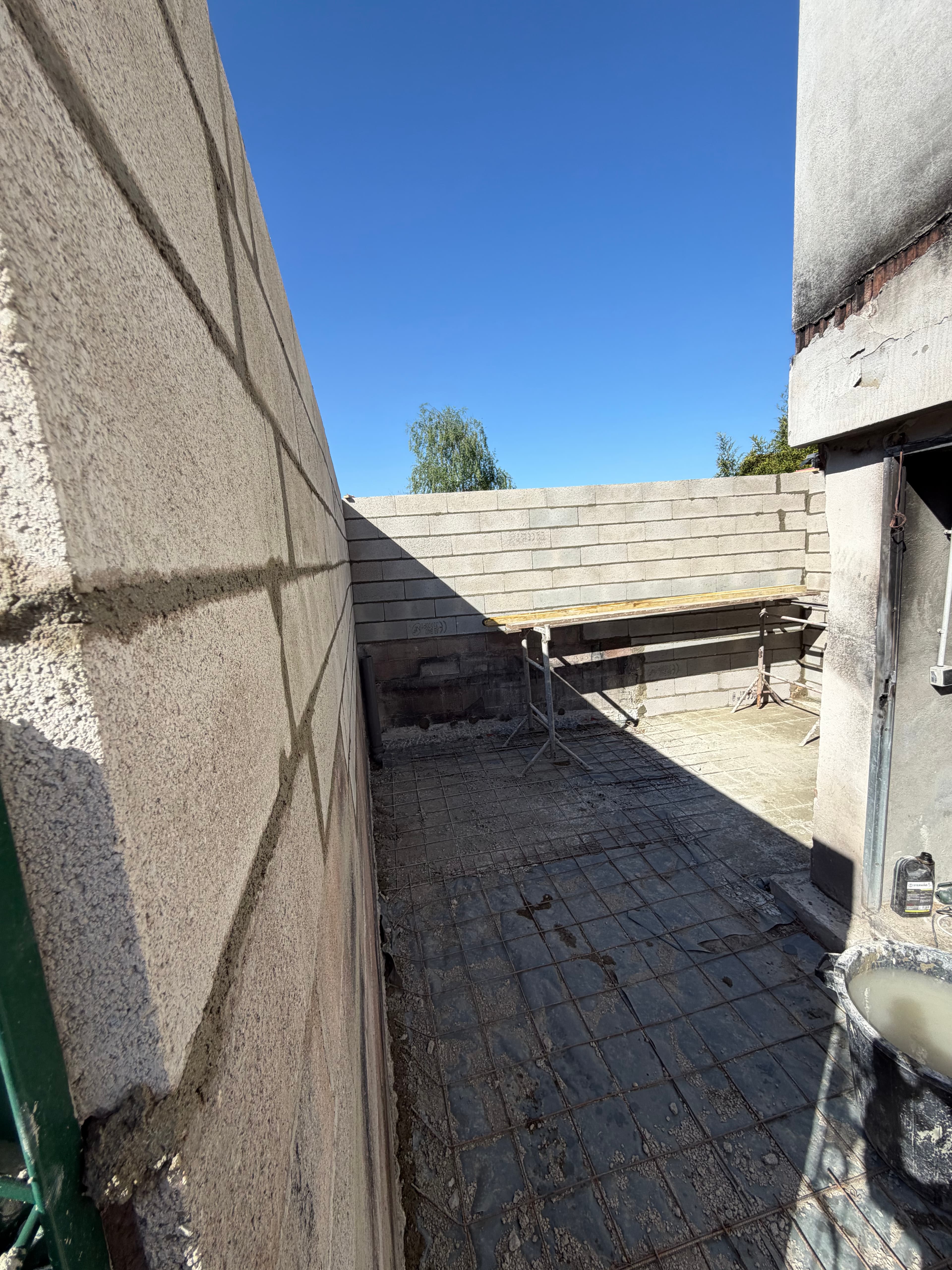 Maçonnerie du muret de délimitation achevée, treillis soudé posé sur film polyane avant coulage.